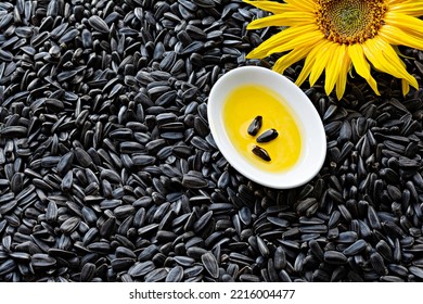 Fresh Sunflower Flower On A Background Of Black Seeds With A Bowl Of Sunflower Oil, Vegetable Oil By Cold Pressing. The Concept Of Vegetable Fats.