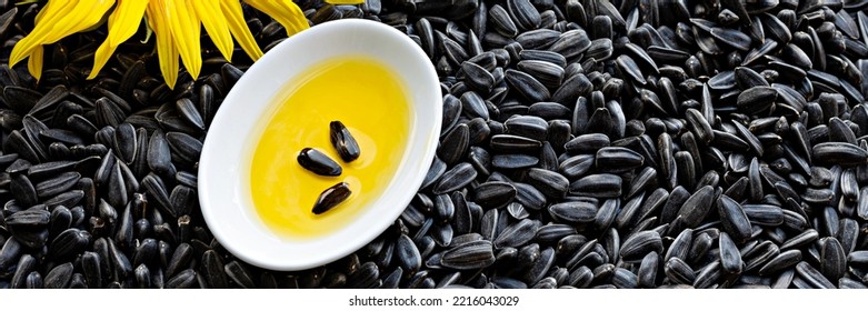 Fresh Sunflower Flower On A Background Of Black Seeds With A Bowl Of Sunflower Oil, Vegetable Oil By Cold Pressing. The Concept Of Vegetable Fats.