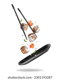 Rollos de sushi frescos con varios ingredientes que caen sobre un plato de arcilla negra