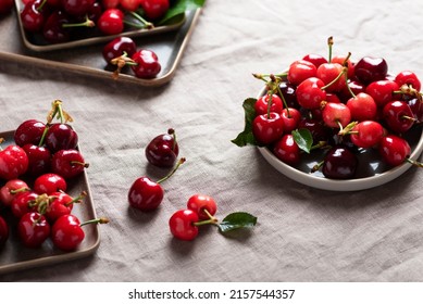 Fresh sweet cherry with green leaves on the linen tablecloth, selective focus image