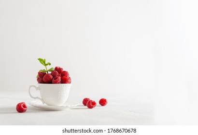 Fresh sweet raspberries in a white cup on white background. Side view, copy space for text. Natural cosmetics, food background. Summer poster, greeting card, sale - Powered by Shutterstock