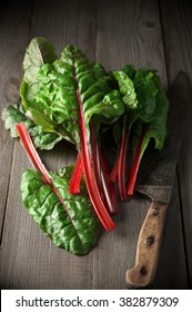 Fresh Swiss Chard Leaves And Vintage Knife On Dark Wooden Table.