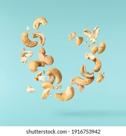Fresh tasty Cashew nuts falling in the air isolated on turquoise background. Food levitation concept. High resolution image.