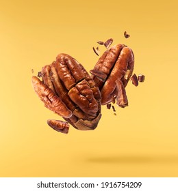 Fresh tasty pecan nuts falling in the air isolated on yellow background. Food levitation concept. High resolution image.