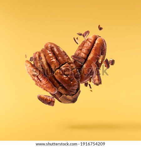 Fresh tasty pecan nuts falling in the air isolated on yellow background. Food levitation concept. High resolution image. 商業照片 © 