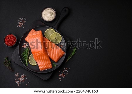 Fresh tasty raw red fish fillet with spices and herbs on a dark concrete background