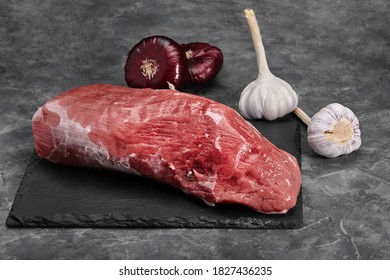 Fresh tenderloin with rosemary, raw meat, top view, on a stone background.