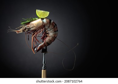 Fresh Tiger Prawn With Rosemary And Lime Slice On A Black Background. Copy Space.