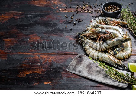Fresh tiger shrimps, prawns with spices and herbs. Black woodenbackground. Top view. Copy space.