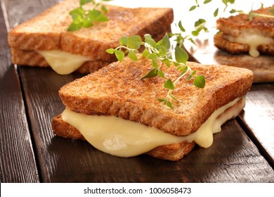 Fresh toast with cheese and herbs on wooden background