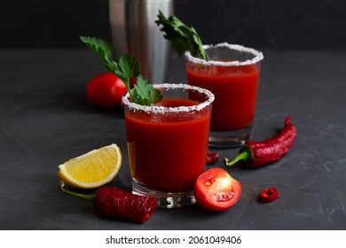 Fresh Tomato juice with pepper, spices, salt and yellow lemon in glass with copy space. Bloody Mary cocktail. Alcoholic drink with vodka, vampiro cocktail and ingredients on the black background.
