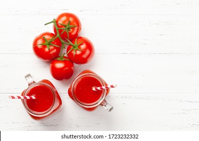 Fresh tomato juice and ripe tomatoes on wooden table. Top view with copy space