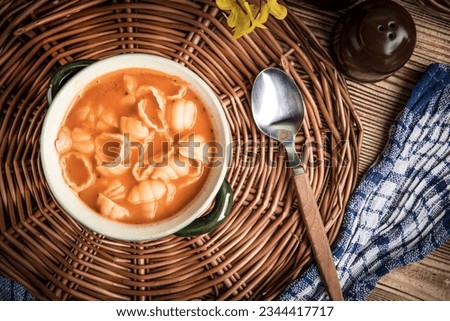 Fresh tomato soup with conchigliette in green bowl.