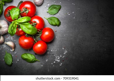 Fresh Tomatoes With Basil Garlic And Sea Salt On Black Slate Background. Top View With Copy Space.