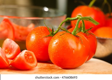 Fresh tomatoes being prepared into a tomato wedge salad on a glass table.