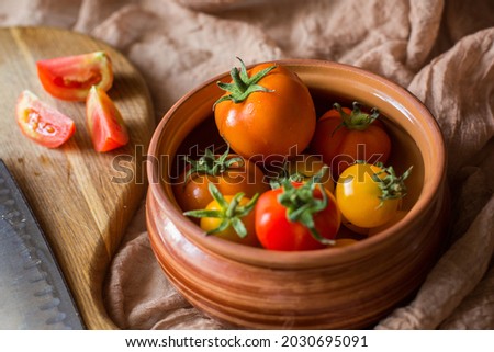 Fresh tomatoes in earthenware. Red, orange and yellow tomatoes on a brown background. Picking tomatoes