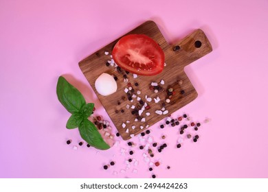 Fresh tomatoes, mozzarella and basil on a pink background. Ingredients for salad. Peppercorns and coarse salt on the surface. Healthy eating. - Powered by Shutterstock