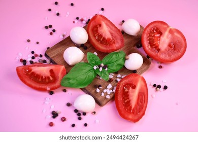 Fresh tomatoes, mozzarella and basil on a pink background. Ingredients for salad. Peppercorns and coarse salt on the surface. Healthy eating. - Powered by Shutterstock