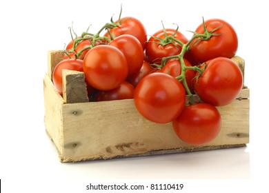 fresh tomatoes on the vine in a wooden crate on a white background