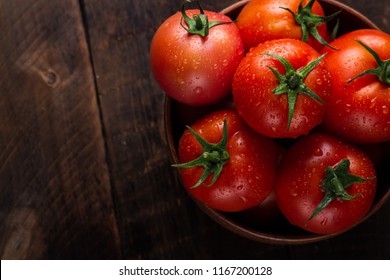 Tomates frescos en un plato sobre un fondo oscuro. Cosechando tomates. Vista superior