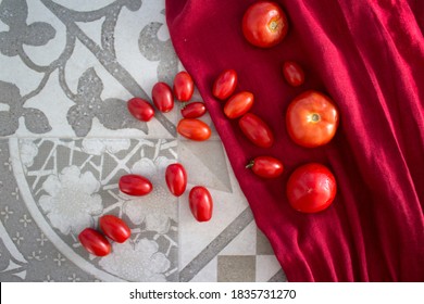 Fresh tomatoes of two different types on red kitchen towel. Top view photo with copy space. Healthy eating concept. 