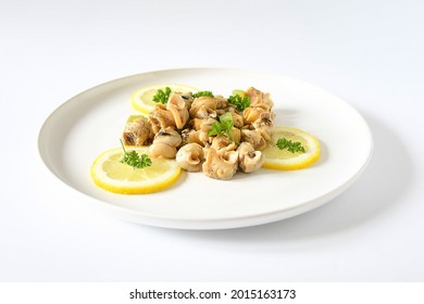 Fresh top view whelks's cook or sea snails in a white plate, piece of lemon ,persil on white background.Food marine gastropod simple various in asia, europe kitchen, seafood concept. Selective focus.