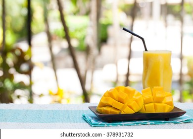 Fresh tropical fruit smoothie mango juice and fresh mango on a outdoor tropical background Copy space