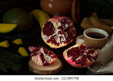 Fresh Tropical Fruits On A Black Background. Pomegranate, Banana, Mango. Fruits With Tea And Honey. The Concept Of A Cozy Family Evening. Comfort And Warmth. Selective Focus