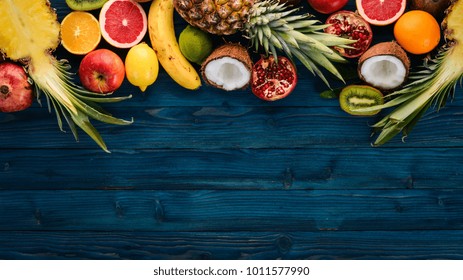 Fresh Tropical Fruits. Pineapple, coconut, kiwi, orange, pomegranate, grapefruit. On a wooden background. Top view. Free space for text. - Powered by Shutterstock