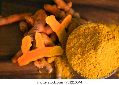 Fresh Tumeric And Tumeric Powder On Wood Cutting Board