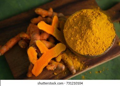 Fresh Tumeric And Tumeric Powder On Wood Cutting Board