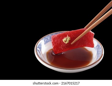 Fresh tuna sliced ​​on wooden chopsticks and wasabi soy sauce, Isolated on a black background