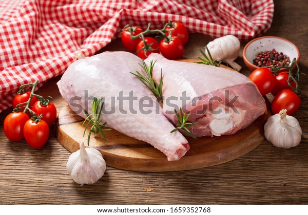 fresh turkey legs with ingredients for cooking\
on wooden background