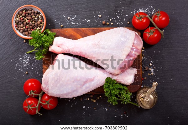 fresh turkey legs with ingredients for cooking on\
dark background, top view