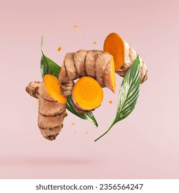 Fresh turmeric root with green leaves falling in the air isolated on pink background. Food levitation conception. High resolution image. - Powered by Shutterstock