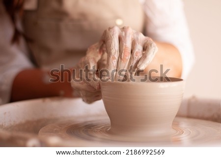 fresh unpainted ceramic bowl on a potter's wheel, ceramist's hands