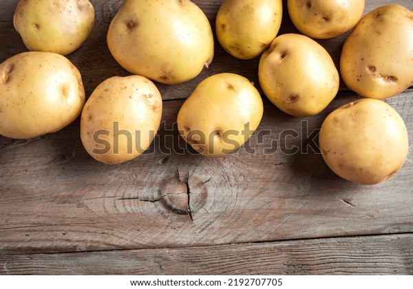 Fresh unpeeled baby potatoes, raw new potatoes\
ready to cook on wooden background close up. Organic farm potato\
for heathy eating.