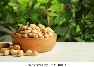 Fresh unpeeled peanuts in bowl on white table against blurred background, space for text - Powered by Shutterstock