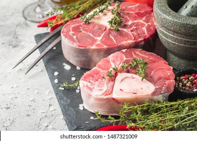 Fresh veal shank slices beef meat for Osso Buco cooking on cutting board with ingredients and seasonings thyme, pepper, salt.