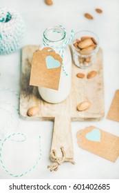 Fresh Vegan Dairy-free Almond Milk In Glass Bottle With Craft Paper Label With Copy Space On Serving Wooden Board Over Light Grey Background. Vegan, Vegetarian, Raw, Clean Eating, Diet Food Concept