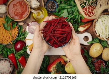 Fresh Vegan Vegetarian Ingredients, Vegetables, Spices, Herbs For Healthy Eating On Rustic Wooden Kitchen Table With Cutting Board. Womens Hands Holding Chopped Beets. Diet, Comfort Food Cooking 