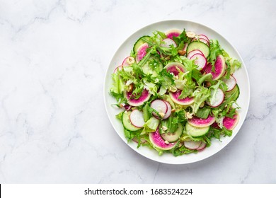 Fresh vegan watermelon radish and  cucumber salad on white plate, top view, copy spase - Shutterstock ID 1683524224