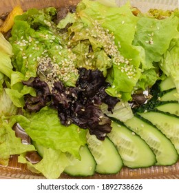 Fresh Vegetable Salad Close-up. Green And Burgundy Lettuce Leaves, Chopped Cucumbers, Sesame Seeds. Top View