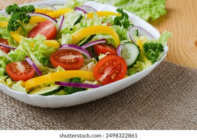 A fresh vegetable salad featuring cherry tomatoes, yellow bell peppers, red onions, cucumbers, and leafy greens, served in a white bowl. - Powered by Shutterstock