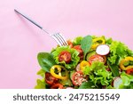 Fresh vegetable salad. Healthy food. Healthy eating concept. Salad on pink background. Top view close up
