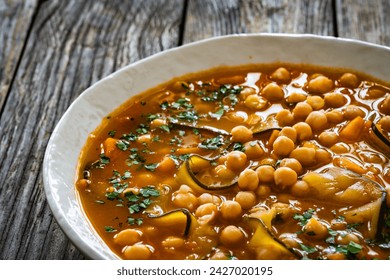 Fresh vegetable soup with chickpeas, zucchini and sweet potatoes on wooden table 