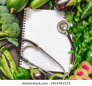 Fresh vegetables are arranged around notebook with stethoscope. Healthy food concept top view. Copy space