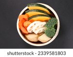 Fresh vegetables in a bamboo steamer on black background, top view