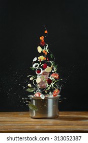 Sayuran segar jatuh ke dalam casserole stainless steel di atas meja kayu. Konsep memasak borsch Foto Stok