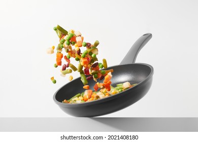 Las verduras frescas vuelan en una sartén sobre un fondo blanco. Cocina con verduras picadas en una sartén. El concepto de alimentación saludable y dieta. 